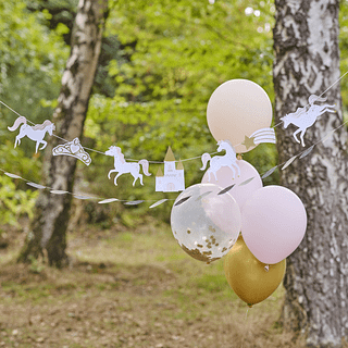 Slinger met paarden, kasteeltjes en een vallende ster hant in een bos naast een setje ballonnen in het lichtroze en perzikkleur