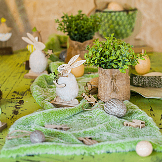 Groene tafelloper op groene en bruine tafel met plantjes en houten konijntjes en hanen