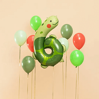 groene schildpad folieballon voor een oranje muur naast gifgroen, olijfgroene en oranje ballonnen