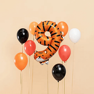 folieballon cijfer 9 tijger voor een lichtoranje muur naast rode, zwarte, witte en oranje ballonnen