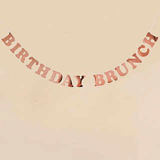 Rose gouden slinger met de tekst birthday brunch op een perzikkleurige muur