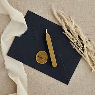 Donkerblauwe envelop ligt op een jute tafelkleed naast graan en is dicht gemaakt met gouden wax