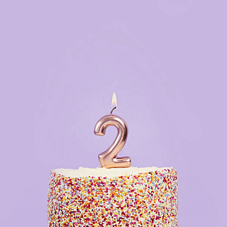rose gouden taart kaars cijfer 2 in een regenboog taart met spikkels voor een paarse muur