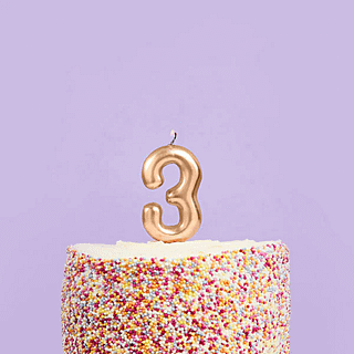 gouden kaars cijfer 3 in een regenboog sprinkle taart voor een paarse achtergrond