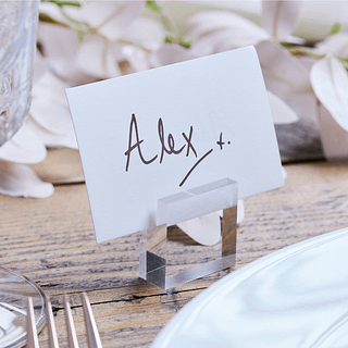 transparante kaarthouder staat op een houten tafel met een wit kaartje met hierop de naam alex