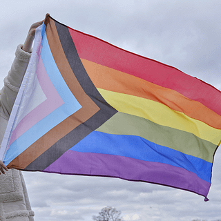 regenboog pride vlag LGBTQ+ wordt buiten vastgehouden voor een bewolkte lucht