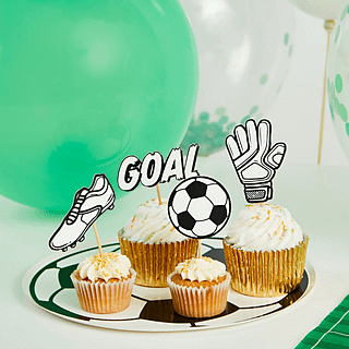cupcake toppers in de vorm van een voetbalscohen, een keepershandschoen, een voetbal en het woord goal zitten in cupcakes en liggen voor een groene ballon