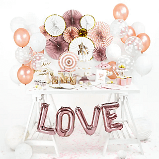 witte tafel met rose gouden versiering en letterballonnen die love spellen
