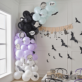 Ballonnenboog met mint, lila, witte en zwarte ballonnen en figuurtjes bestaande uit een vampier, heks, spook en skelet staat voor een witte muur versierd met zwarte vleermuizen en een oranje slinger