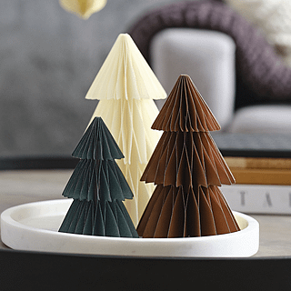 Honeycomb kerstboompjes in het donkergroen, chocoladebruin en creme staan in een wit schaaltje op een zwarte tafel