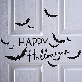 Zwarte stickers happy halloween en vleermuizen zitten op een witte deur