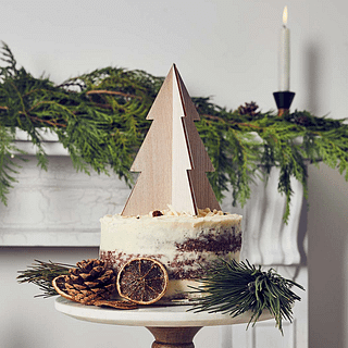 Houten topper in de vorm van een kerstboom staat op een taart