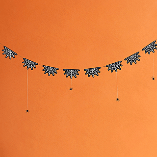 Slinger met spinnenwebben en spinnetjes in het zwart en wit hangt voor een oranje achtergrond