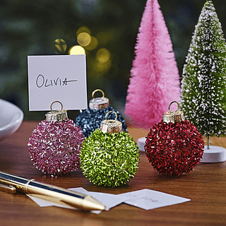 Kerstballen met glitters in het roze, rood, groen en blauw staan op een houten tafel voor een felroze kerstboom