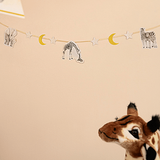 Slinger hangt aan de muur boven een knuffel giraffe