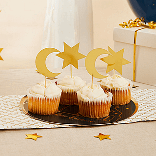 Cupcakes op een zwart bord versierd met gouden prikkers met sterren en maantjes erop
