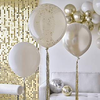 Ballonnen in het champagne goud, nude en taupe met gouden tassels zweven in een versierde woonkamer met gouden en nude versiering