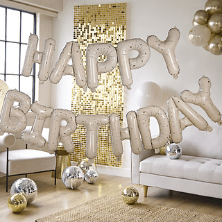 Happy birthday ballonnen in het nude en goud hangen voor een gouden backdrop