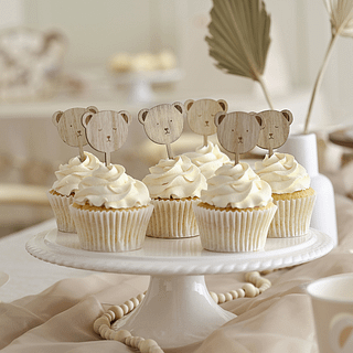 Houten teddy beren cupcake toppers zitten in cupcakes versierd met witte creme