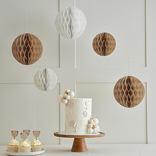 Bruine en creme honeycombs hangen boven een witte taart op een houten plateau
