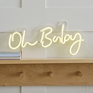 Lichtgevend bordje met de tekst oh baby hangt boven een houten kapstok