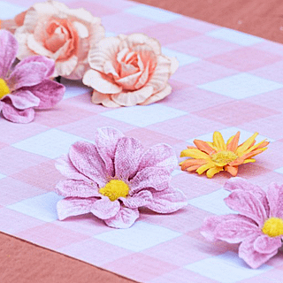 Roze en wit geblokte tafelloper versierd met oranje en roze bloemen