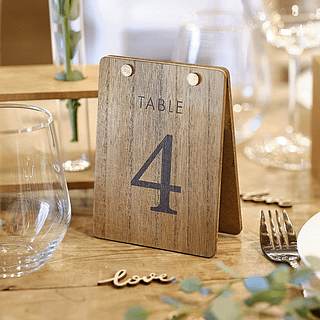 Houten tafel nummer staat op een houten tafel met botanische versiering