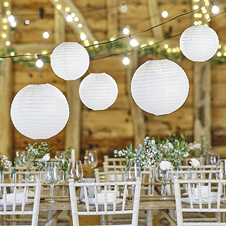 witte lampionnen hangen boven een rustiek versierde bruiloft tafel