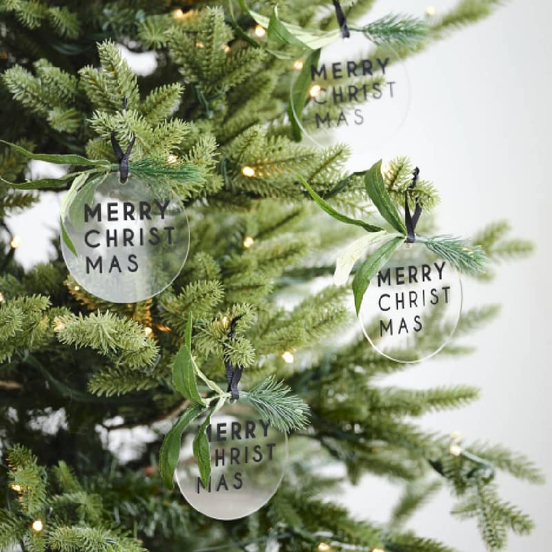 Kerstboom met daarin lampjes en transparante merry christmas hangers