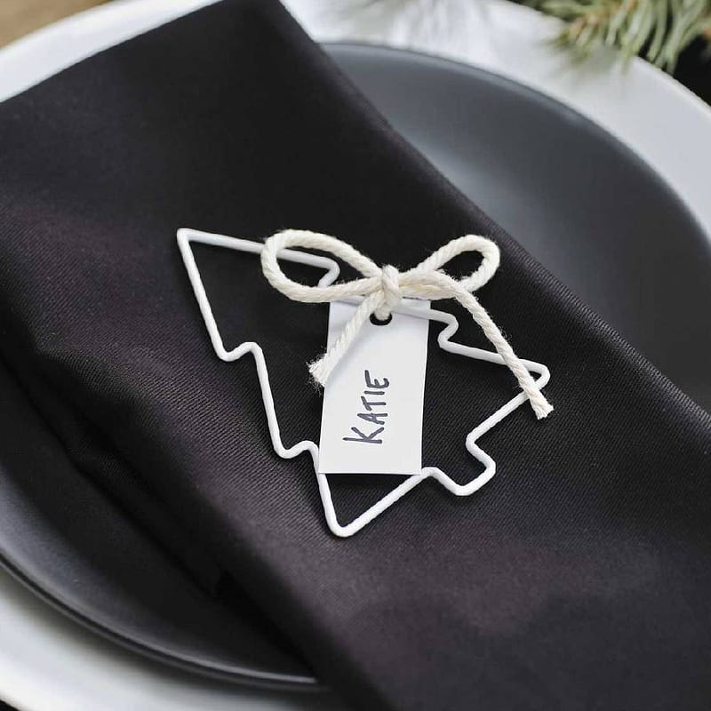 Wit tafelkaartje in de vorm van een kerstboompje op een zwart servet