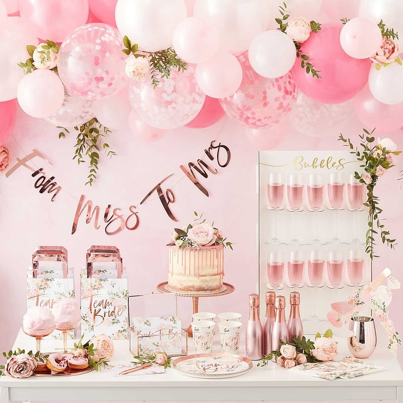 Tafel met vrijgezellenfeest versiering, champagne, taart en een ballonnenboog erboven