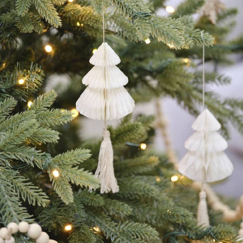 Kerstboom met witte honeycomb hangers erin in de vorm van een kerstboom