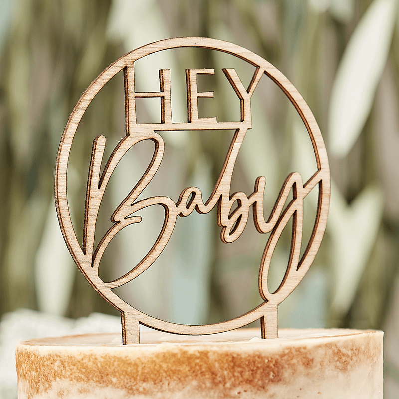 Taart versierd met houten ronde taarttopper met de tekst 'Hey baby'