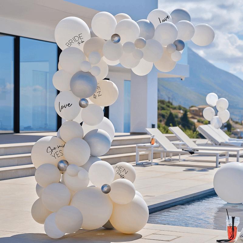 Ballonnenboog met witte en zilveren ballonnen staat naast een zwembad
