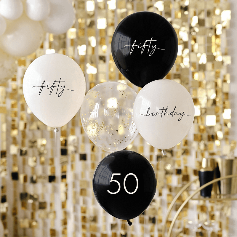 Ballonnen in het nude en zwart voor 50 jaar en een confettiballon met gouden confetti zweven voor een gouden backdrop