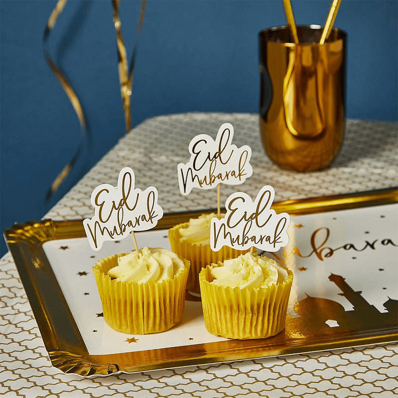 Cupcakes staan op een gouden schaal en zijn versierd met goud met witte sateprikkers met de tekst eid mubarak
