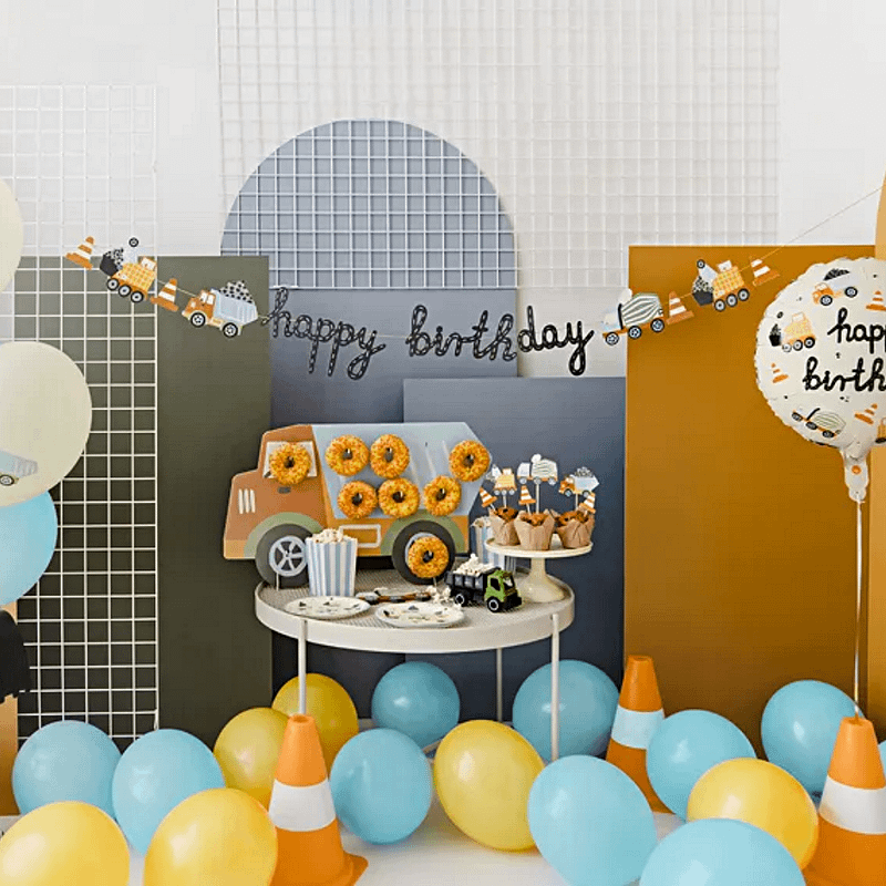 mini ballonnen in het blauw, oranje en geel liggen om een tafel met vrachtwagen en bouwmaterialen feestartikelen