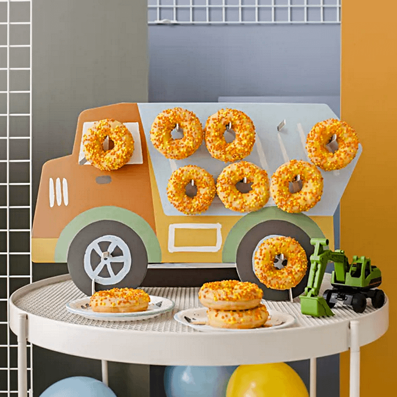 donut standaard in de vorm van een vrachtwagen gevuld met donuts op een witte tafel
