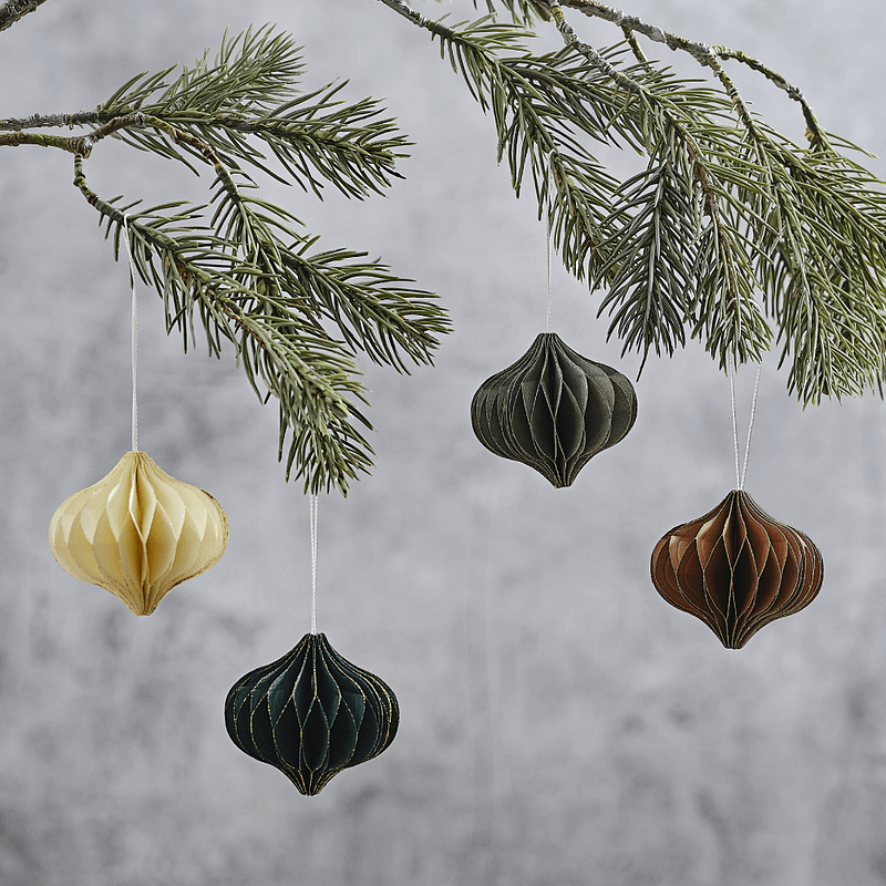 honeycomb hangers in de kleuren creme, groen, grijs en chocoladebruin hangen aan een kerstboom met groene naalden voor een grijze muur