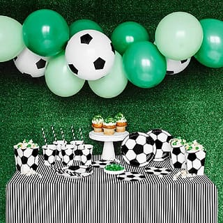 Tafel met voetbal bordjes bekers en servetten, en een voetbalthema ballonnenboog