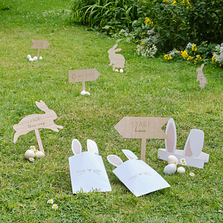 Houten konijnen op een groen grasveld met gele bloemen en paaseieren