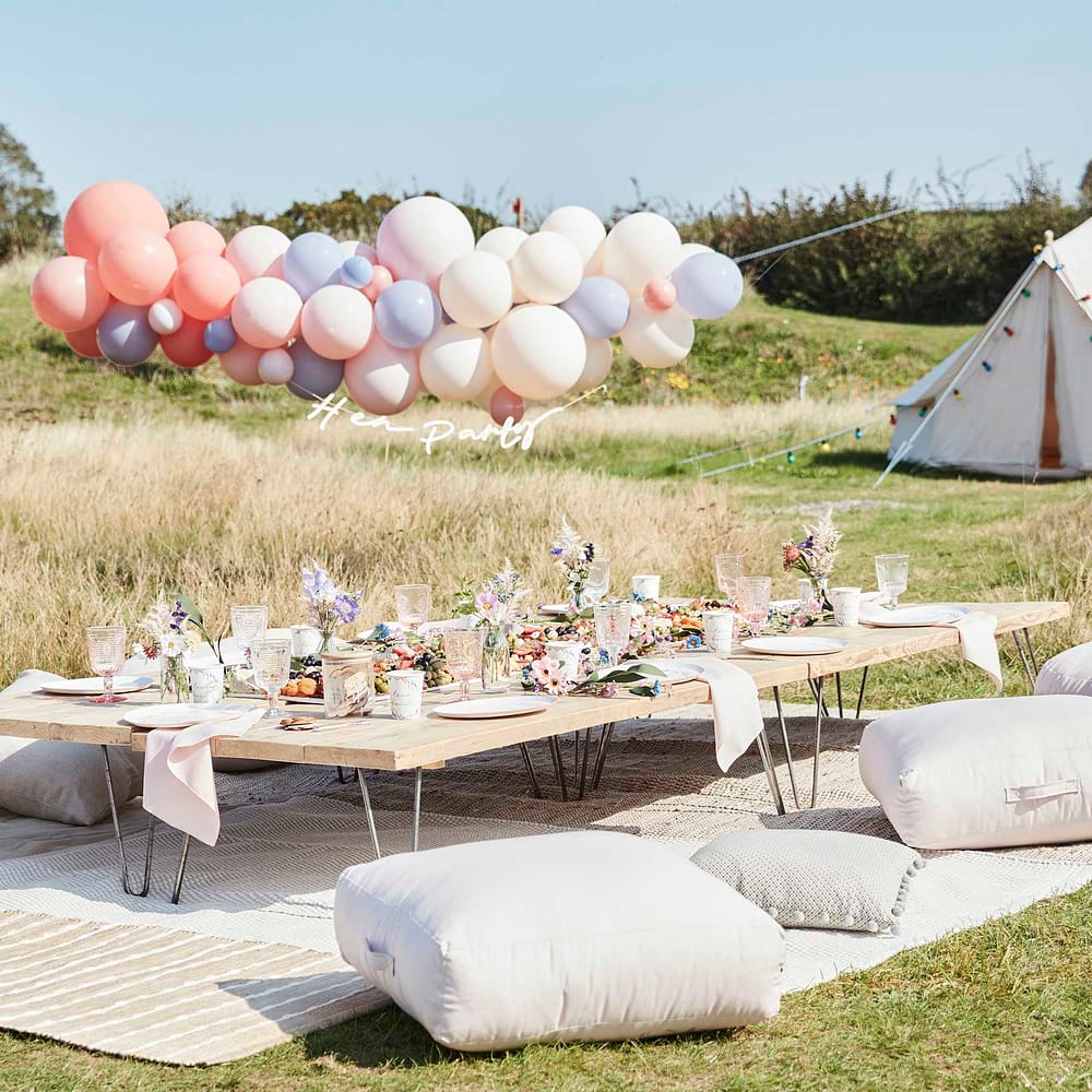 gedekte lage tafel met grote kussens een tent en een boog met ballonnen