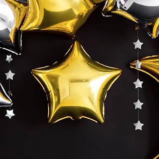Gouden stervormige folieballon op een zwarte achtergrond met zilveren sterrenslinger