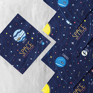 Donkerblauwe servetten met de tekst space adventure en een kaart van de ruimte liggen op een lichtgrijze achtergrond