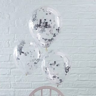 Drie transparante ballonnen met daarin zilveren confetti vastgemaakt aan een stoel