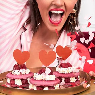 Vrouw met macarons versierd met rode cupcake prikkers met hartjes