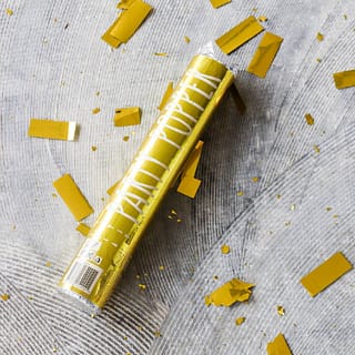 Gouden confettishooter op de grond met gouden confetti eromheen