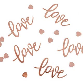 Confetti op tafel in de vorm van het woord love en kleine rose gouden hartjes