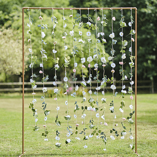 Roségouden decoratieve boog op een grasveld met slingers van kunstbloemen