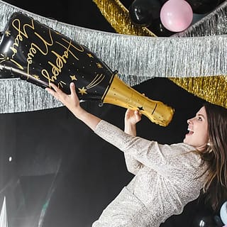Vrouw met folieballon in de vorm van een champagnefles